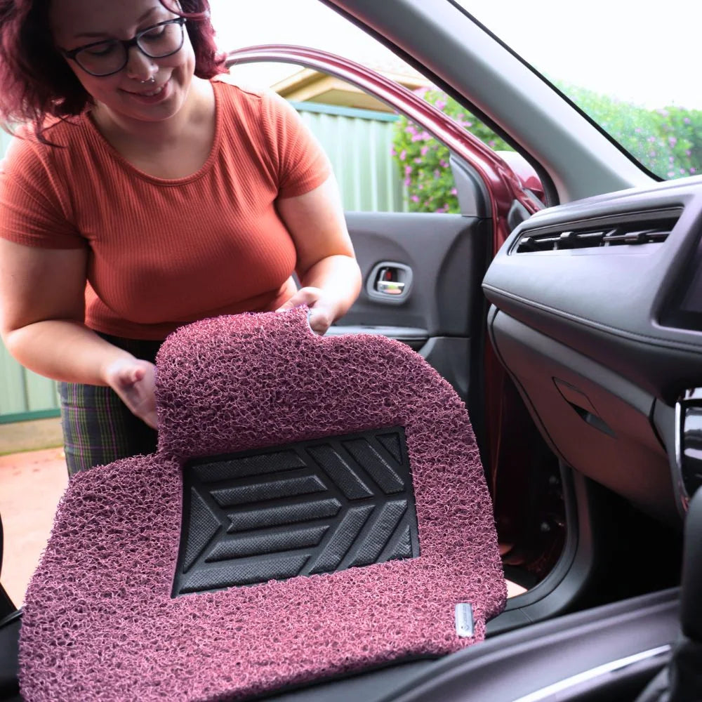 Customer holding a pink AeroLoop mat beside the vehicle